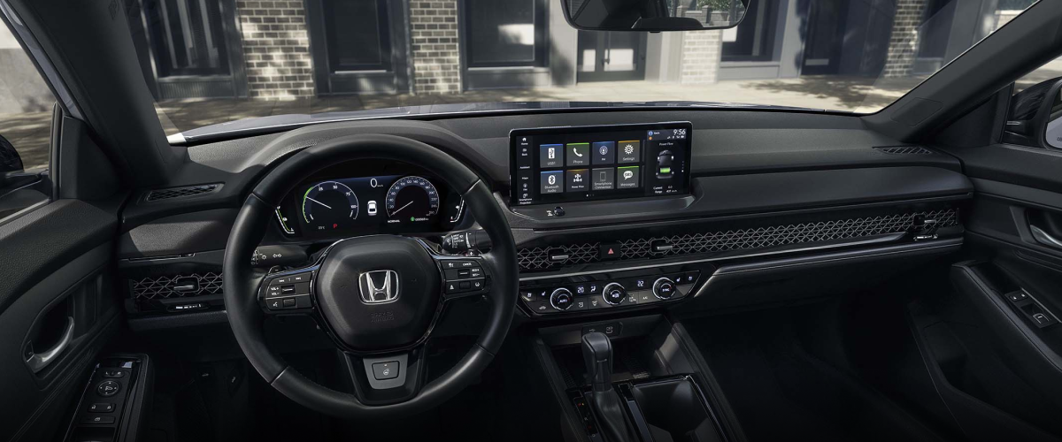 Panoramic wide view of steering wheel and dashboard. Trendy condo building can be seen through the windshield.
